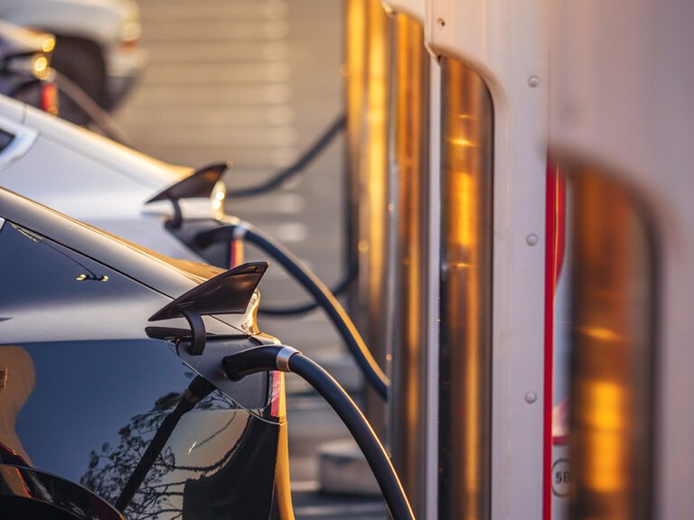 Electric cars charging at charging station outdoors at sunset.