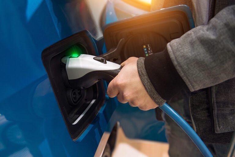 Man charging electro car at charging station. Man holding in han