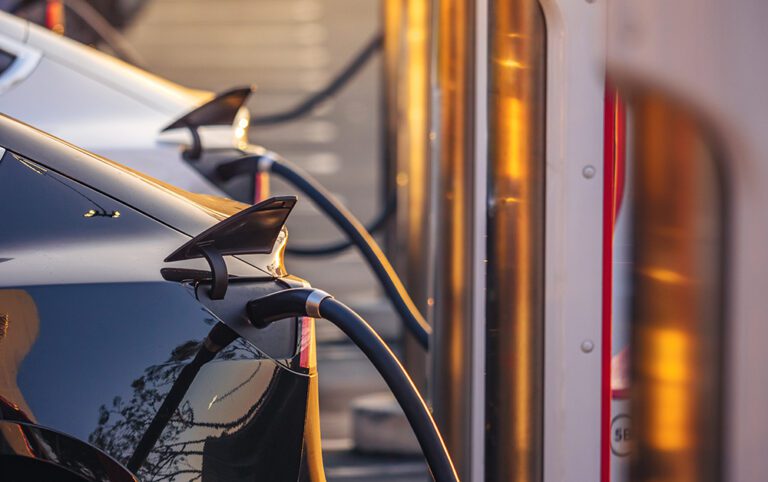 Electric cars charging at charging station outdoors at sunset.