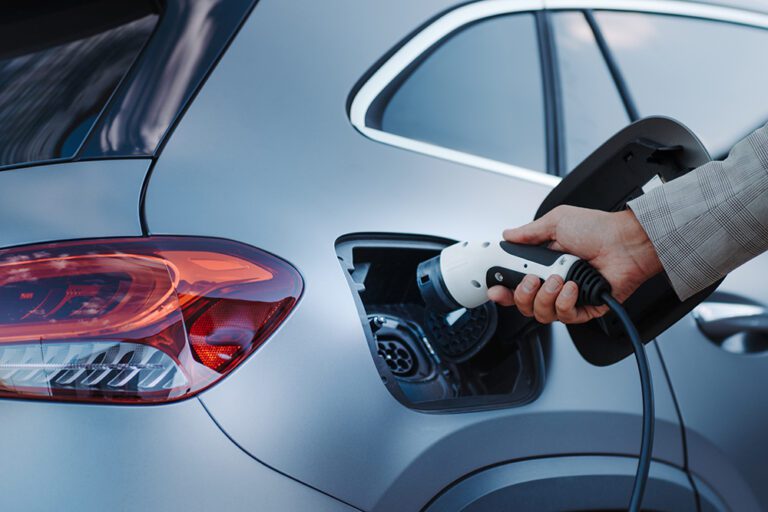 Man holding power supply cable at electric vehicle charging station, closeup