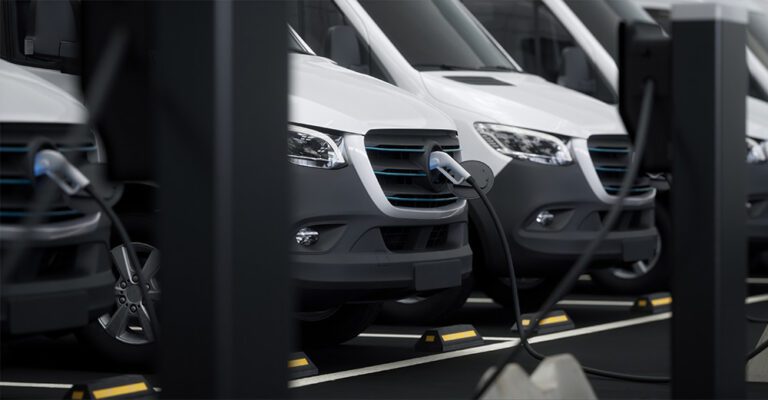 Fleet of generic electric EV delivery vans charging on charging stations